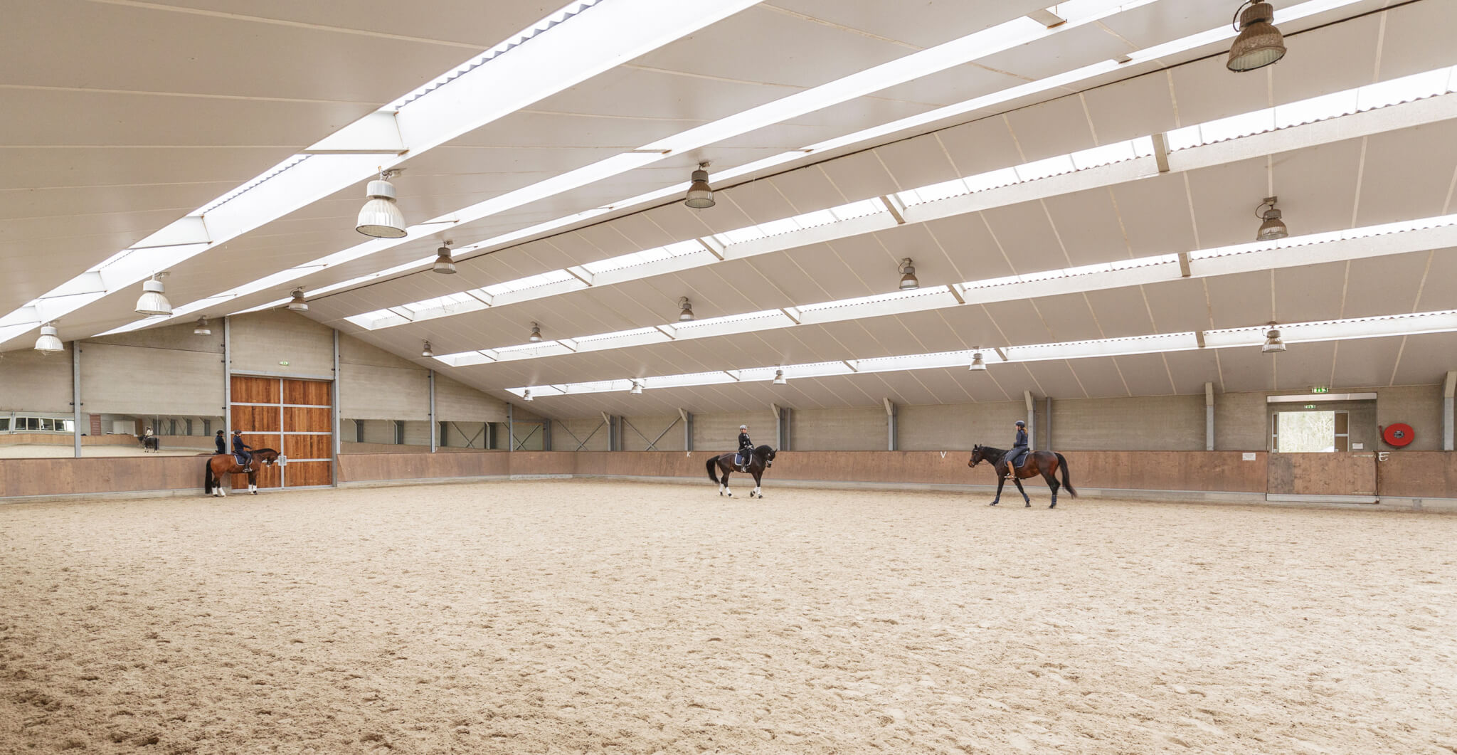 Riders working in a bright indoor arena