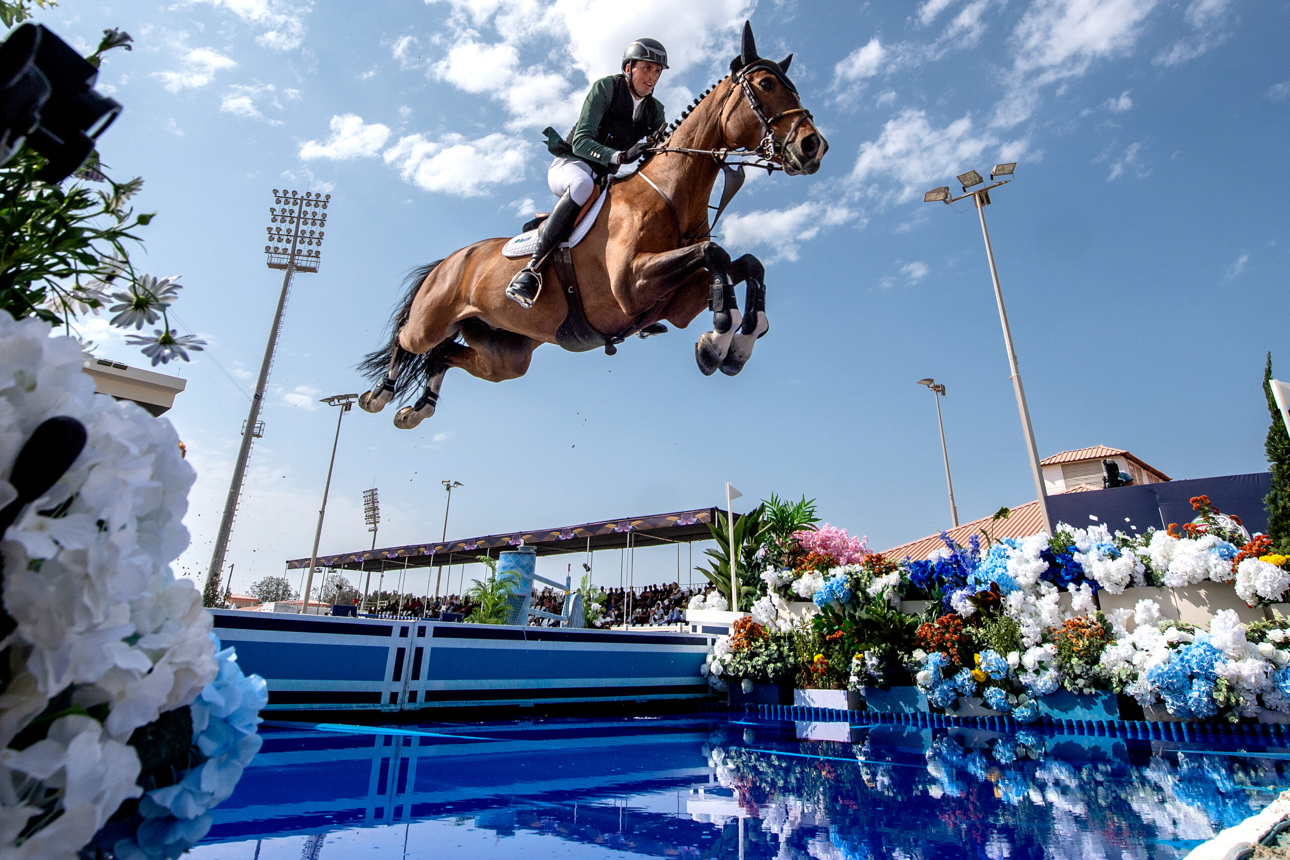 Horse and rider clearing a water jump at a show